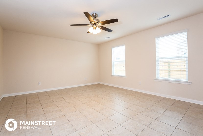 the spacious living room with ceiling fan and tile flooring