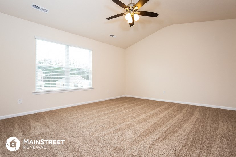 the spacious living room with carpeting and a ceiling fan