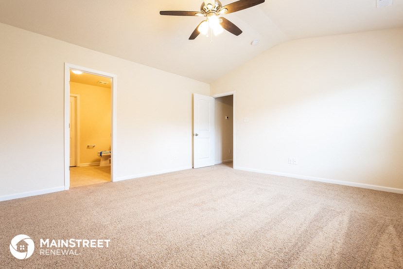 an empty living room with a ceiling fan and white walls