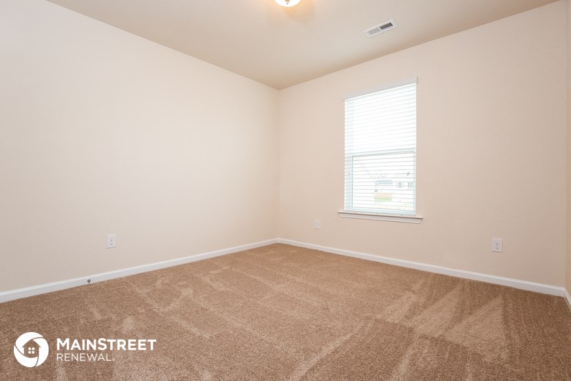 the upstairs bedroom with carpeting and a window