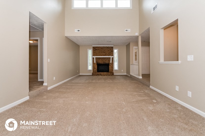 a living room with a carpeted floor and a fireplace