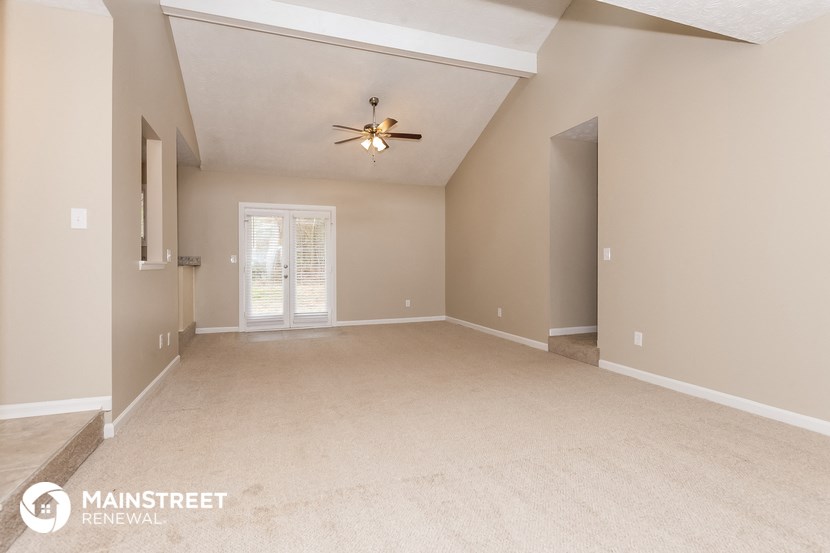the spacious living room with a ceiling fan