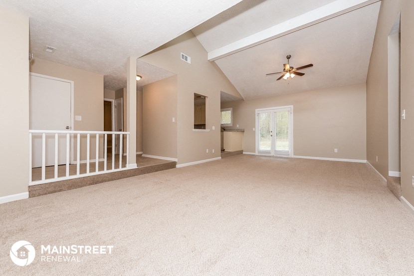 an empty living room with a ceiling fan