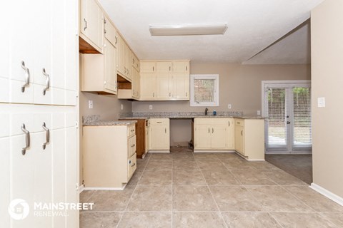 a large kitchen with white cabinets and tile flooring