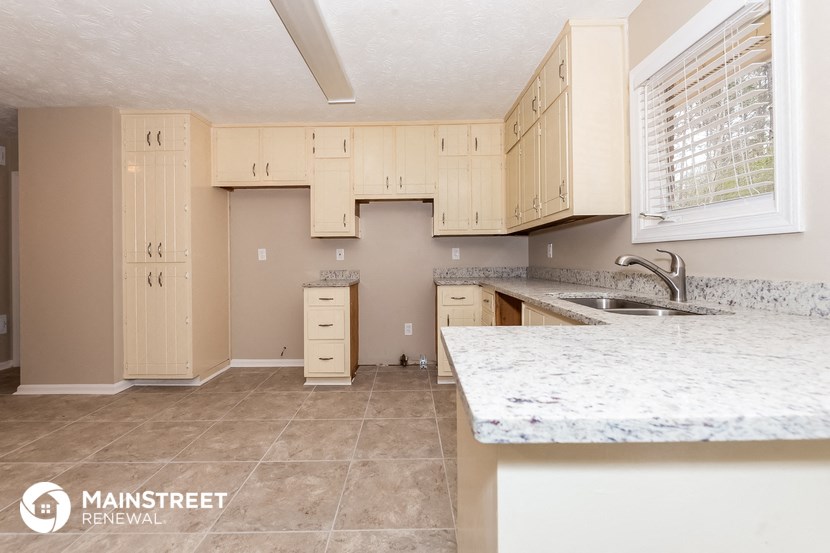 a kitchen with white cabinets and a marble counter top