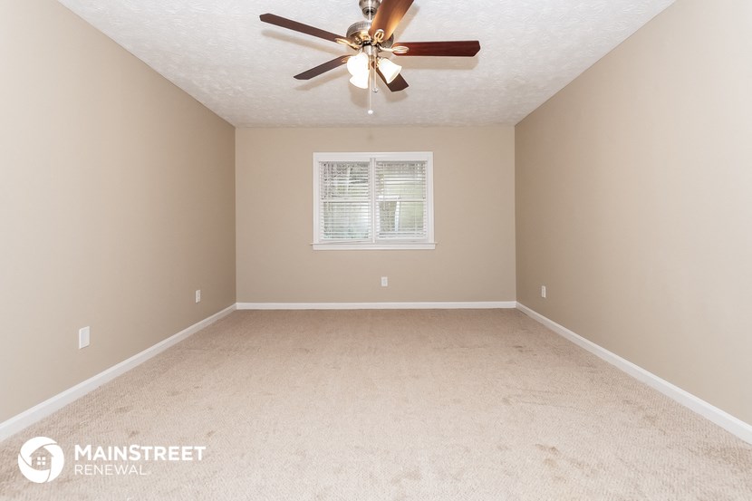 the master bedroom has a carpeted floor and a ceiling fan