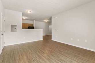 the living room and kitchen of an empty apartment with wood flooring