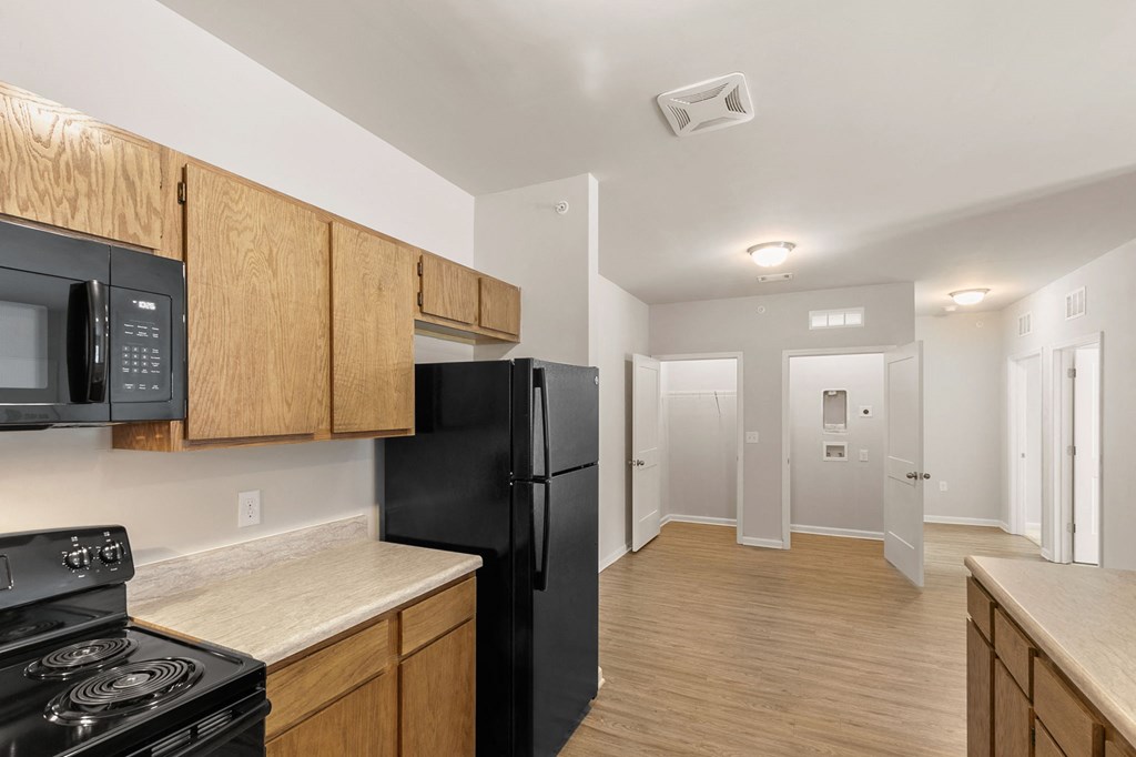 a kitchen with black appliances and wooden cabinets and a black refrigerator