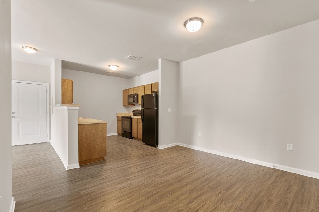 a renovated living room and kitchen with a wood floor and white walls