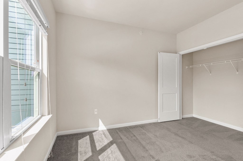 an empty bedroom with a window and a closet