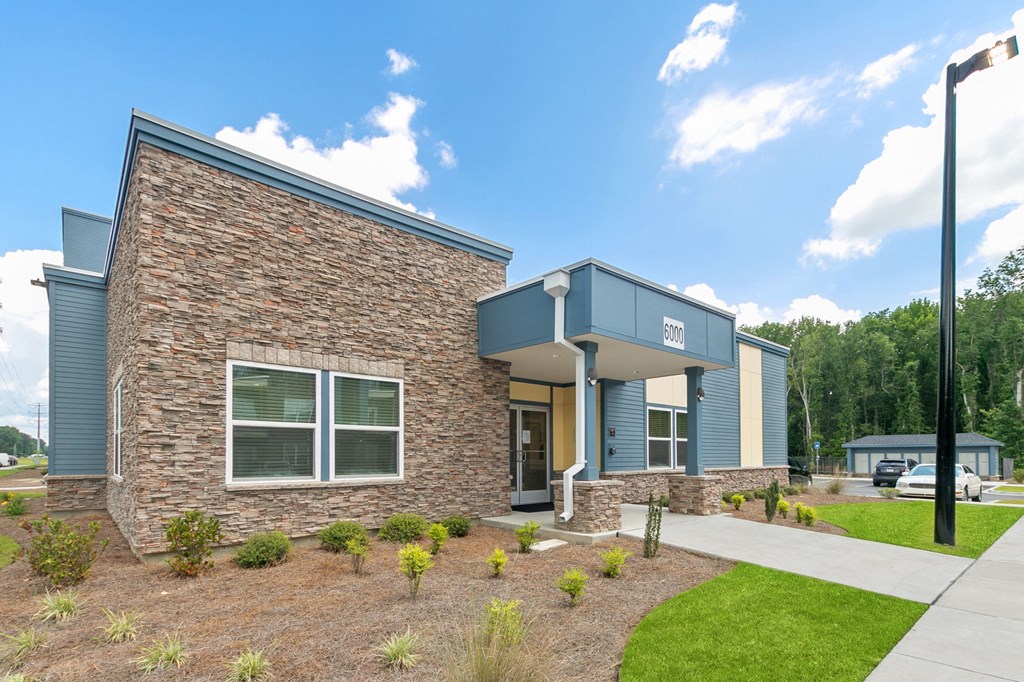 the front of a building with a sidewalk and grass