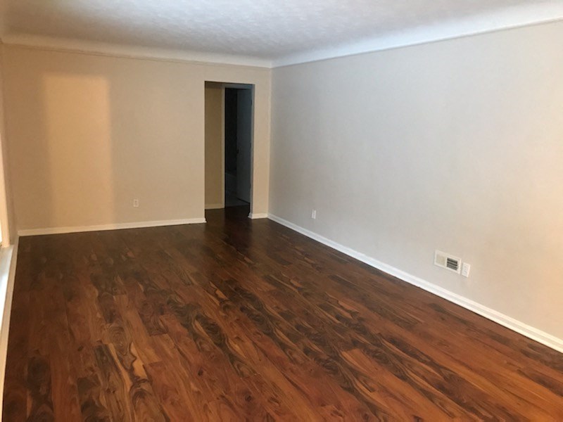 an empty living room with wood flooring and white walls