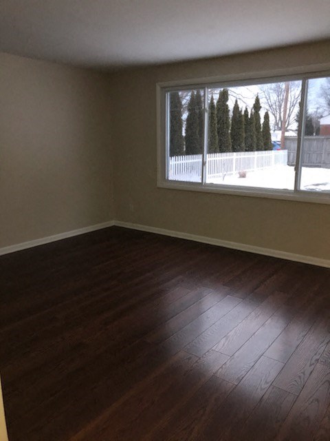 an empty living room with a large window and wooden floors