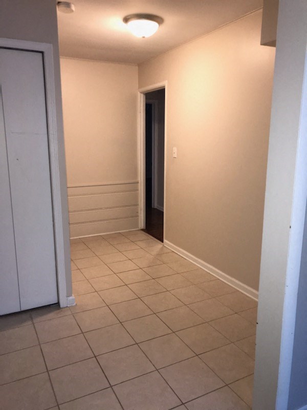 a hallway with a tiled floor and a door to a closet