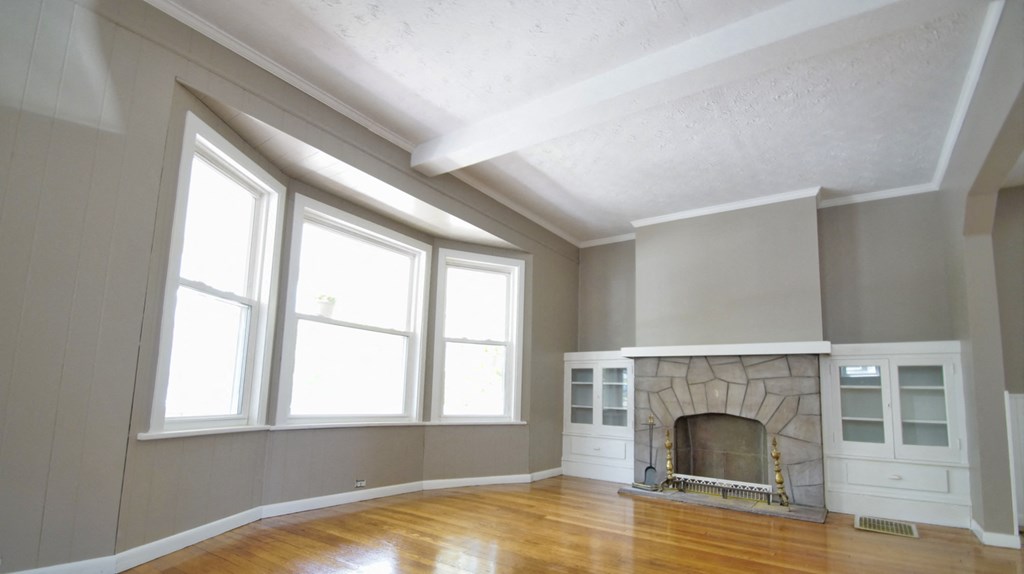 an empty living room with a fireplace and large windows