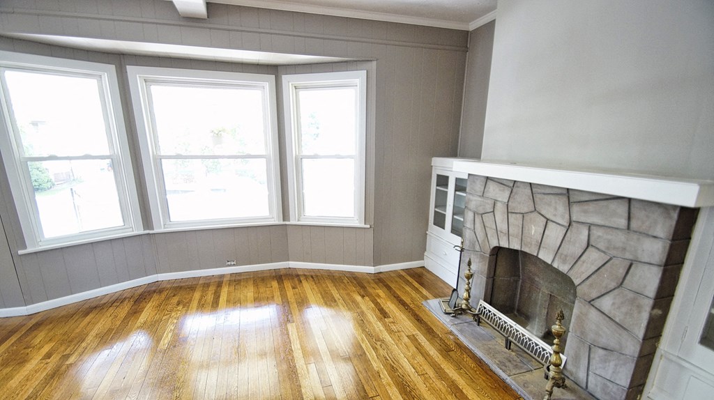 a living room with a stone fireplace and wooden floors