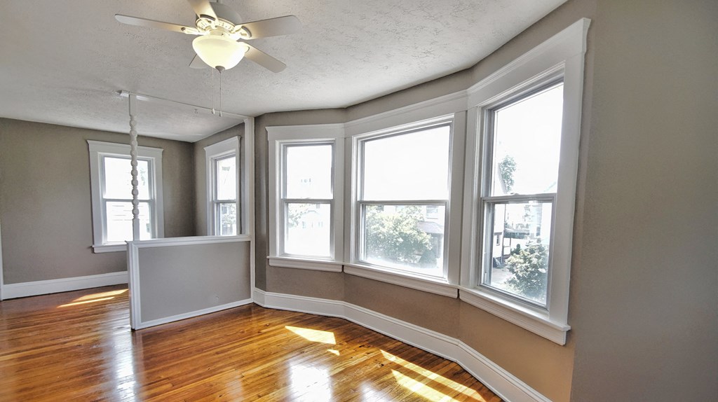 an empty living room with large windows and a ceiling fan
