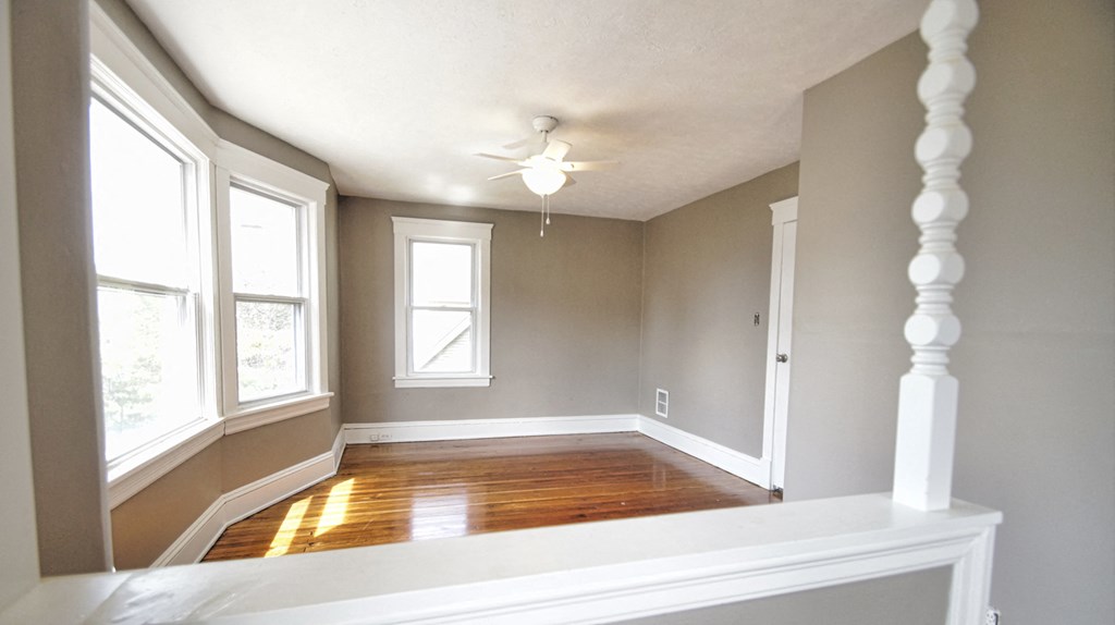 an empty living room with a ceiling fan and windows