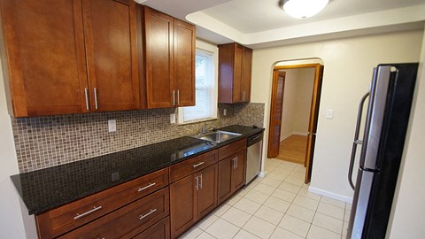 A kitchen with brown cabinets and a black refrigerator.
