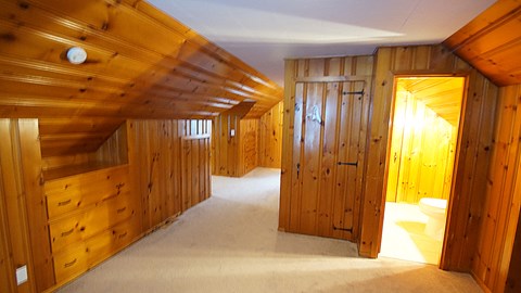 A room with wooden walls and ceiling with a light on.