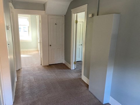 an empty hallway with three doors and a carpeted floor
