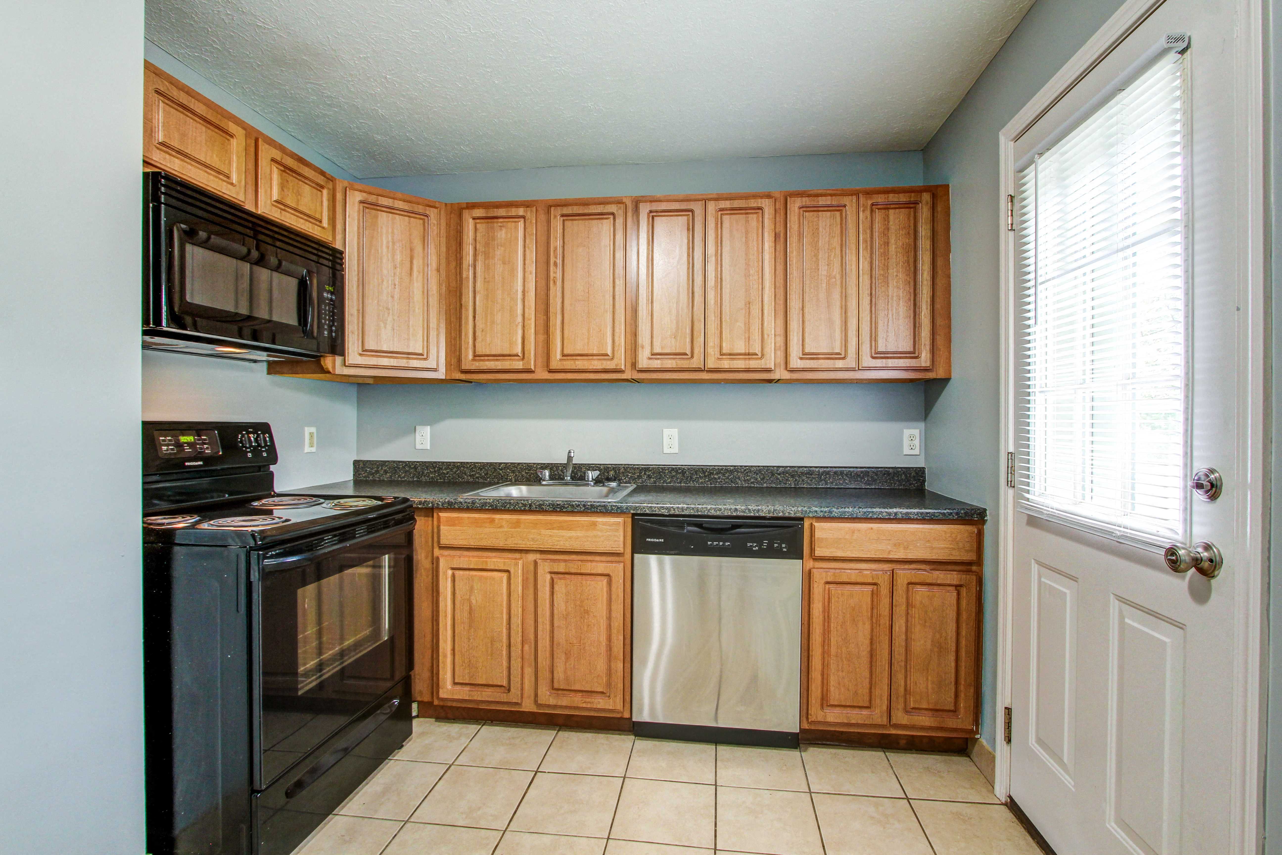 a kitchen with wooden cabinets and black appliances and a sink