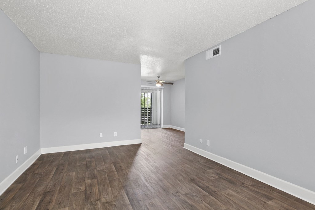 the spacious living room and dining room with hardwood flooring and a sliding door