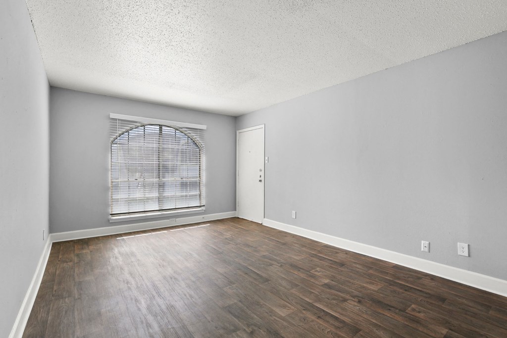 an empty living room with wood flooring and a window