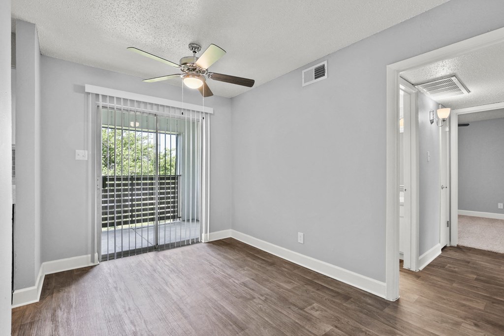 an empty living room with a large window and a ceiling fan