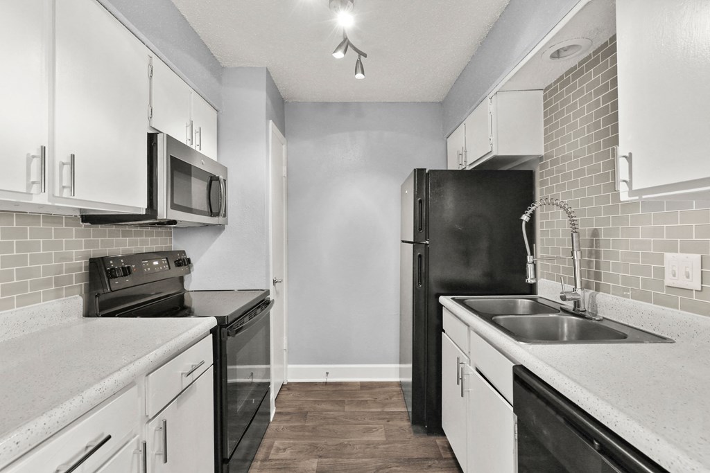 an empty kitchen with black appliances and white cabinets