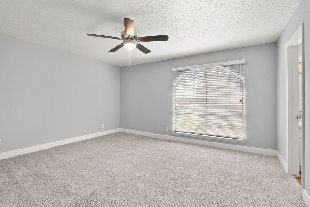 an empty living room with a ceiling fan and a window