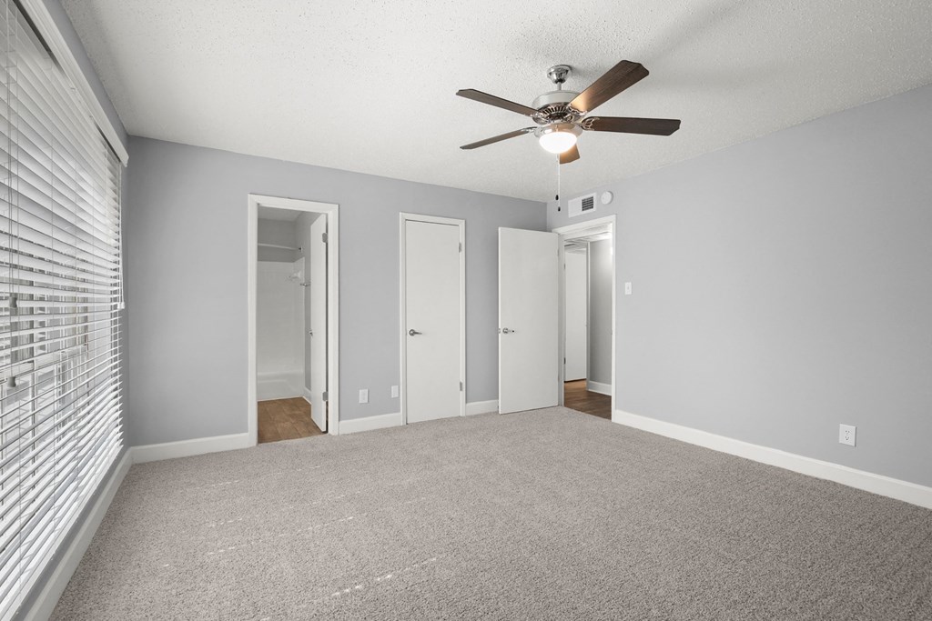 an empty living room with a ceiling fan and a window