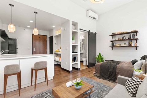 A modern living room with a grey sofa, wooden chairs, and a coffee table.
