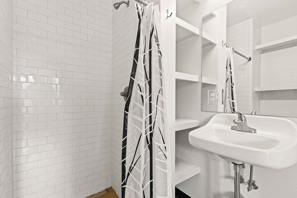 A white bathroom with a white sink and a white shower curtain.