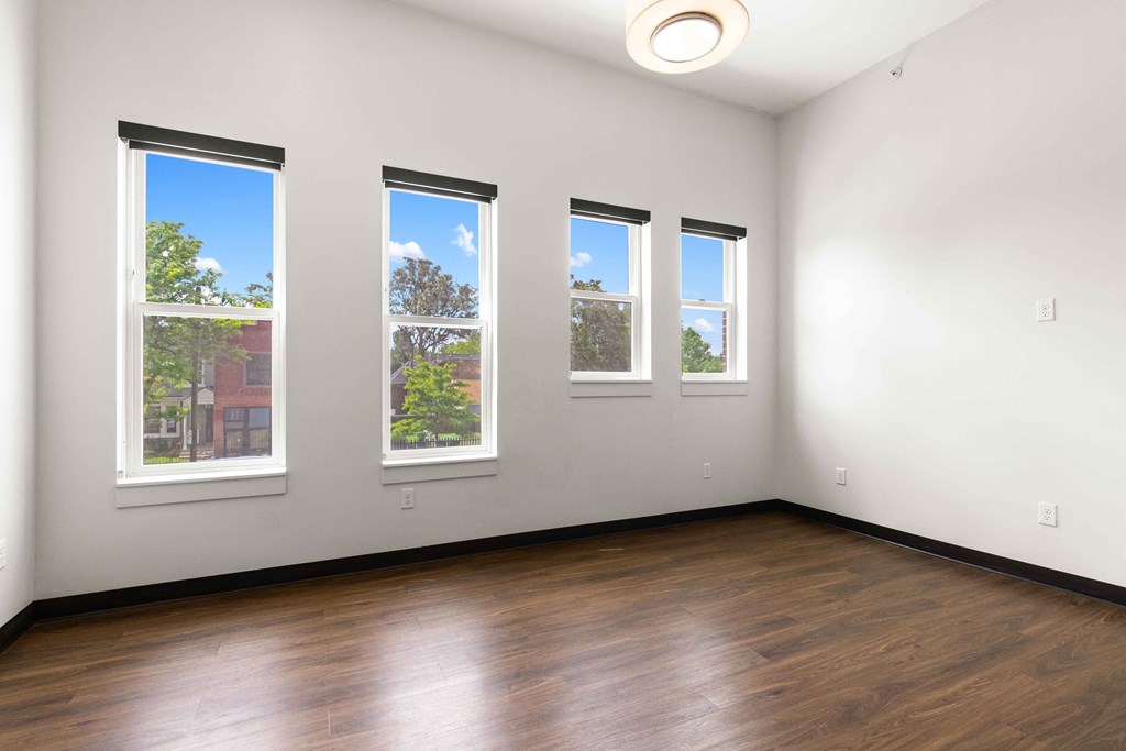 Three windows in a room with wood floors and white walls.