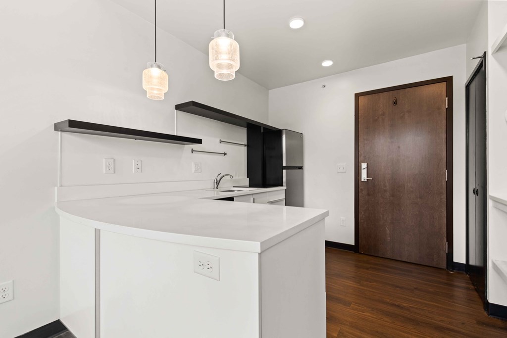 A modern kitchen with white cabinets and a wooden door.