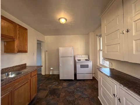 A kitchen with a white refrigerator and a white stove top oven.