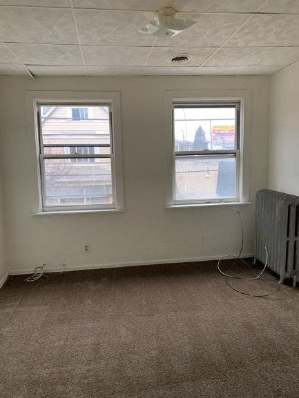an empty room with two windows and a radiator