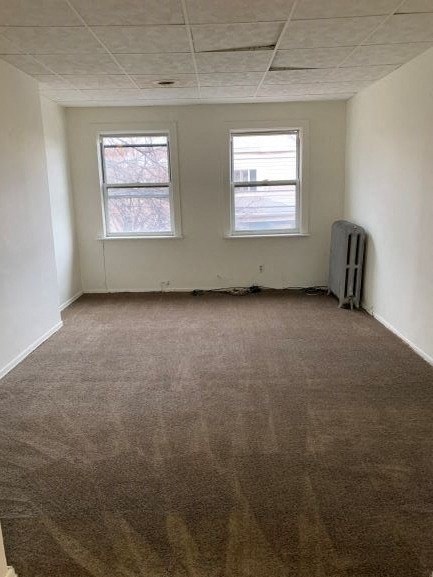 an empty room with a carpeted floor and two windows