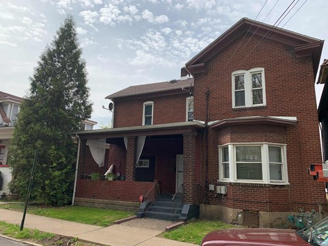 A red brick house with a white window and a black door.