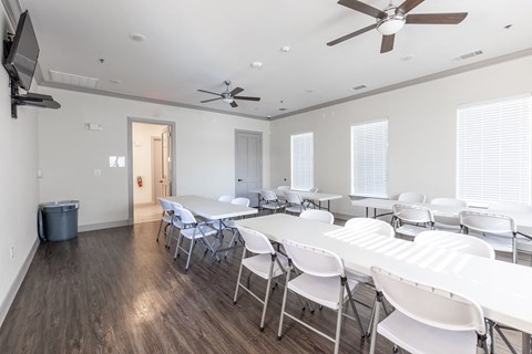 a dining room with white tables and chairs and a ceiling fan