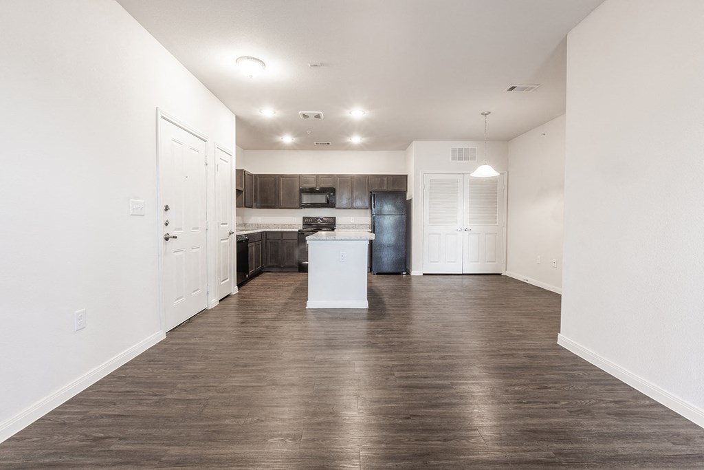 a renovated living room and kitchen with white walls and wood flooring
