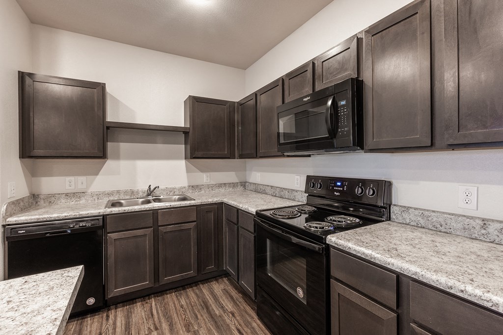 a kitchen with dark wood cabinets and granite counter tops