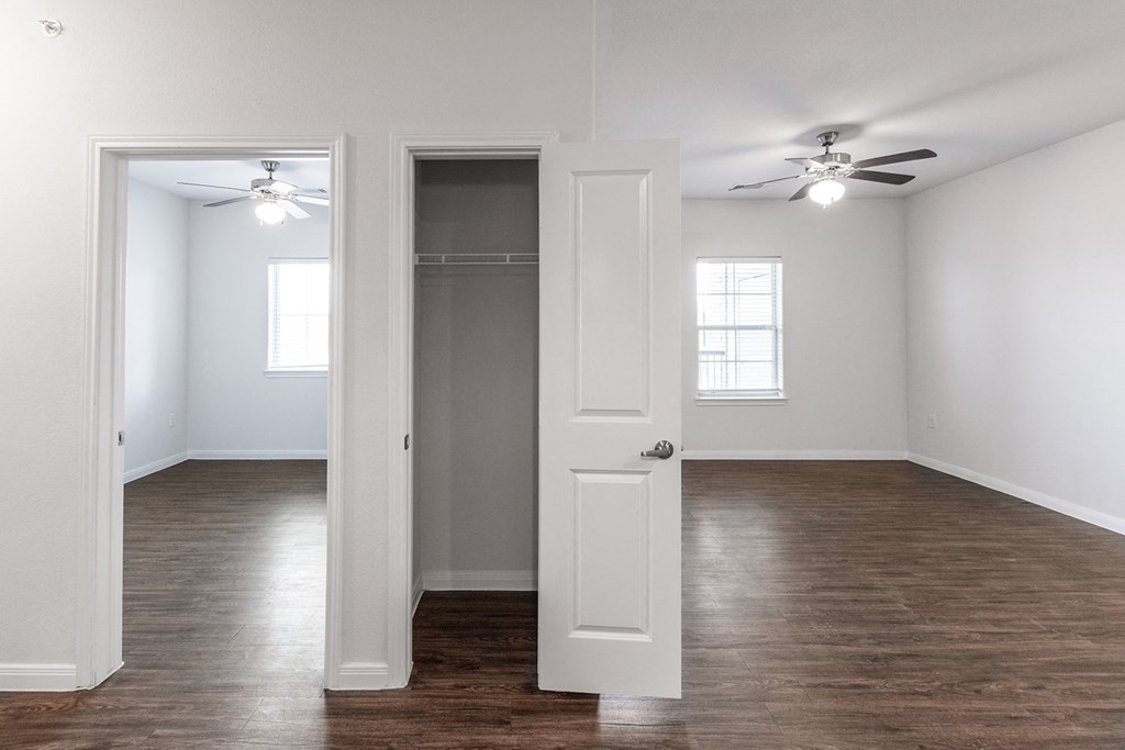 an empty living room with a closet and a ceiling fan