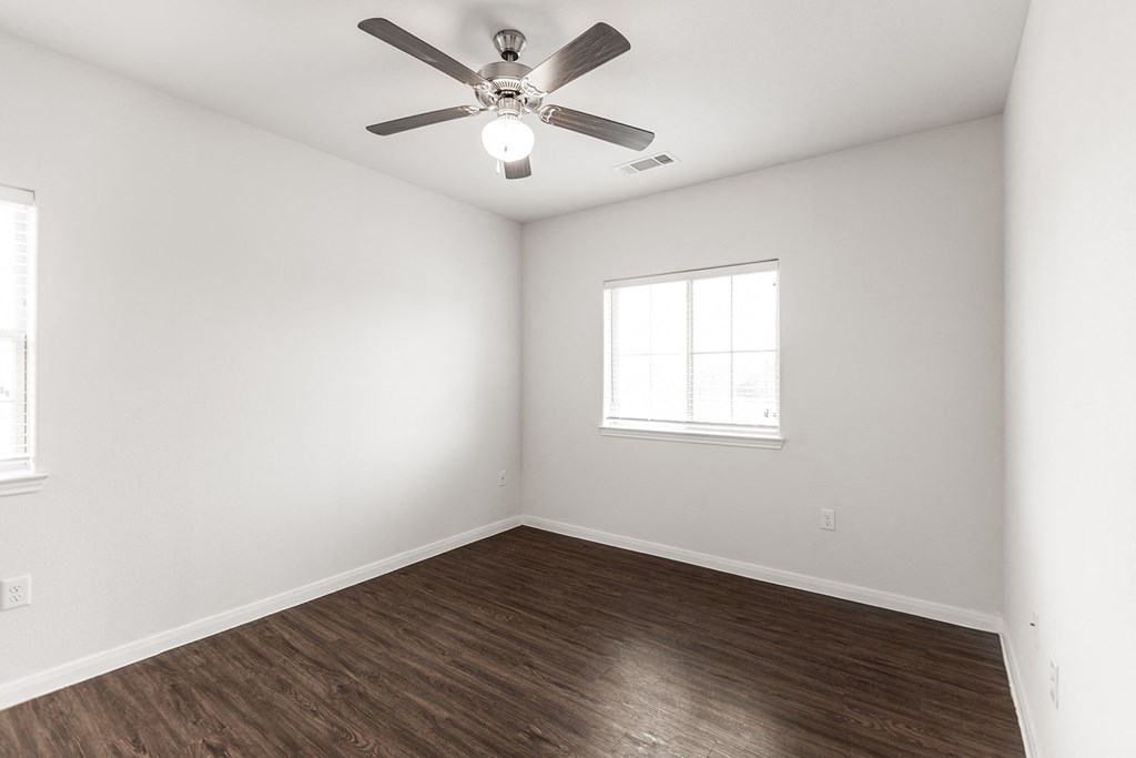 an empty room with white walls and a ceiling fan