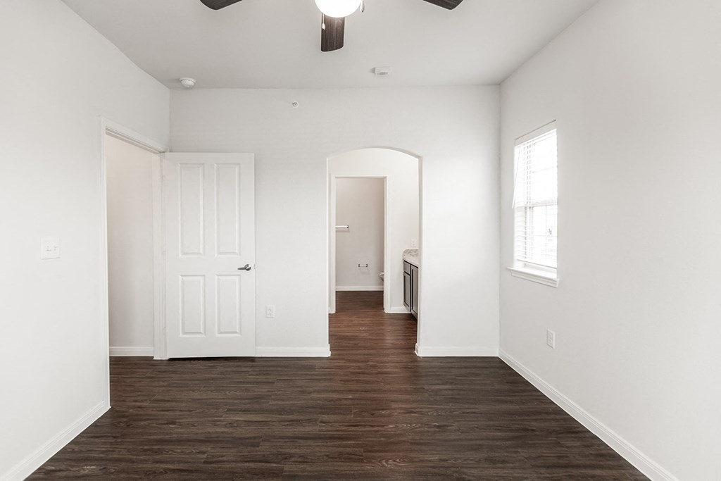 an empty bedroom with white walls and wood flooring