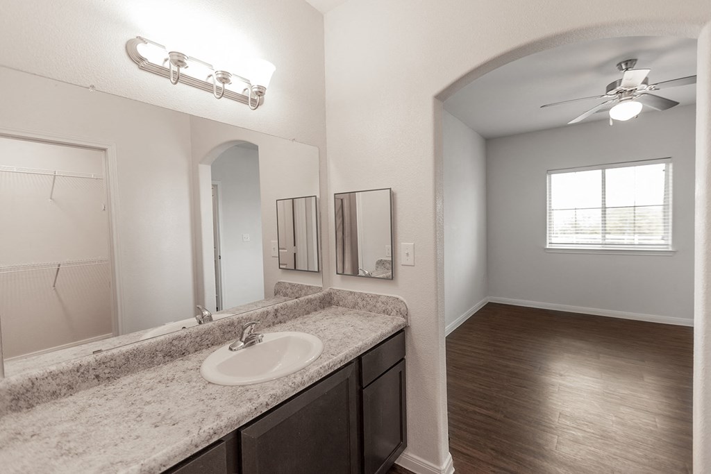 an open living room and bathroom with a sink and a mirror