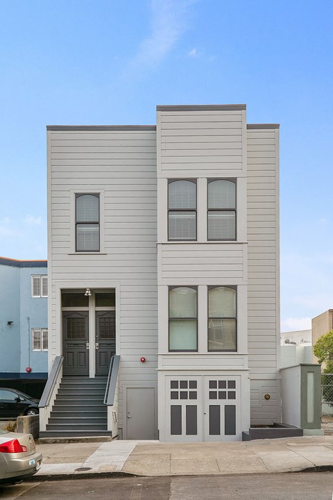 the front of a white house with stairs and a door