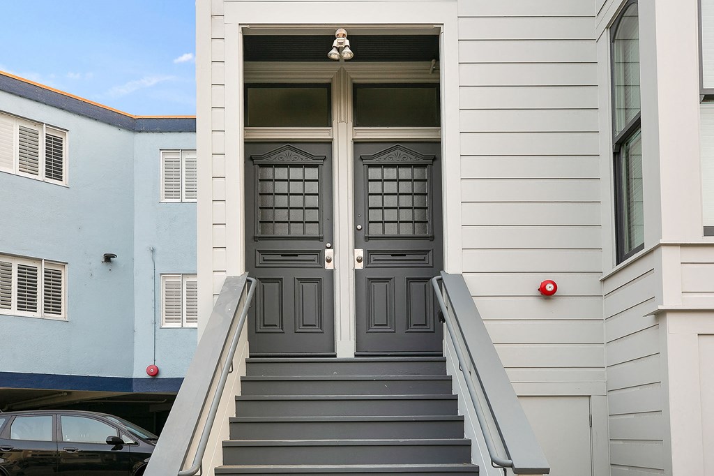 the front of a house with a black door and stairs