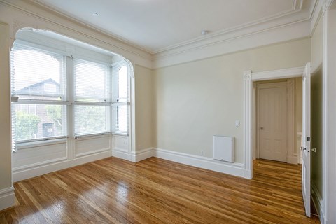 an empty living room with wood flooring and large windows